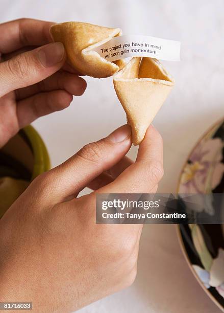 asian girl opening fortune cookie - palmistry hand stock-fotos und bilder