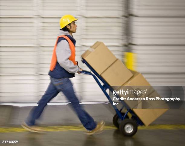 asian warehouse worker pushing boxes on hand truck - helmet cart stock pictures, royalty-free photos & images