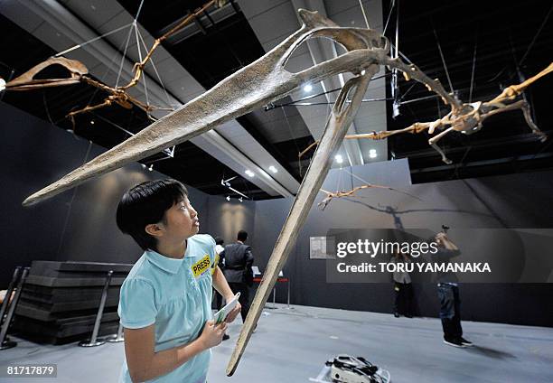 Student Kanna Yamazaki and reporters look at a replica of a skeleton of Quetzalcoatlus during a press preview of the Ptetosaur Exhibition at the...