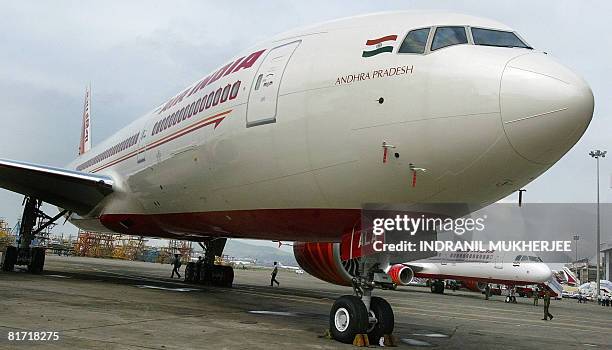 In this picture taken on July 30 Indian security personnel walk past Air India's newly acquired Boeing 777-200 LR aircraft "Andhra Pradesh" and an...