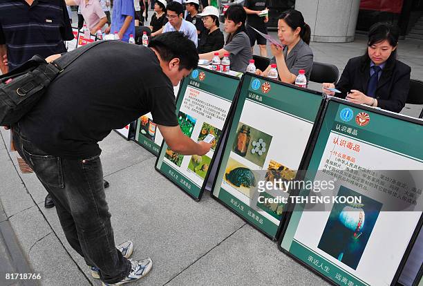 Pedestrian uses his mobile phone to take photos of anti-drug posters on display ahead of the UN's anti-drug day in Beijing on June 26, 2008. China...