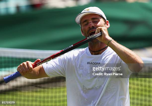 Stefano Galvani of Italy bites his racquet during the round two men's singles match against Mikhail Youzhny of Russia on day four of the Wimbledon...
