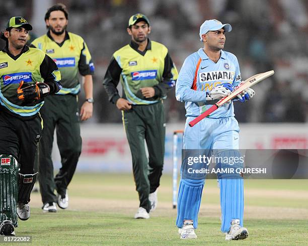 Indian cricketer Virender Sehwag walks back to the pavilion after his dismissal as Pakistani cricketeters look on during a Group B match between...