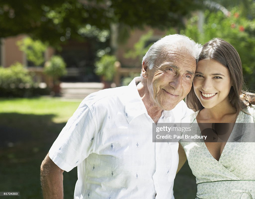 Senior man standing outdoors with arm around woman smiling