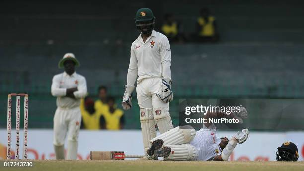 Zimbabwe cricketer Regis Chakabva looks as Sri Lankan batsman Kusal Mendis lies down due to a cramp in his leg during the 4th day's play in the only...