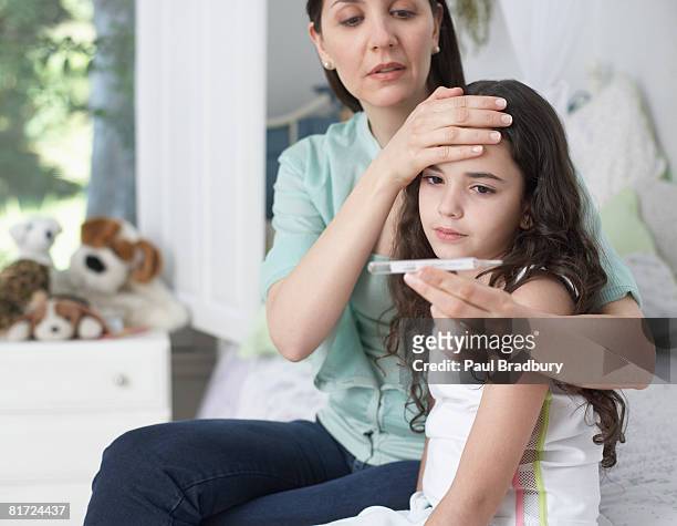 woman in bedroom taking young girls temperature - illness stock pictures, royalty-free photos & images