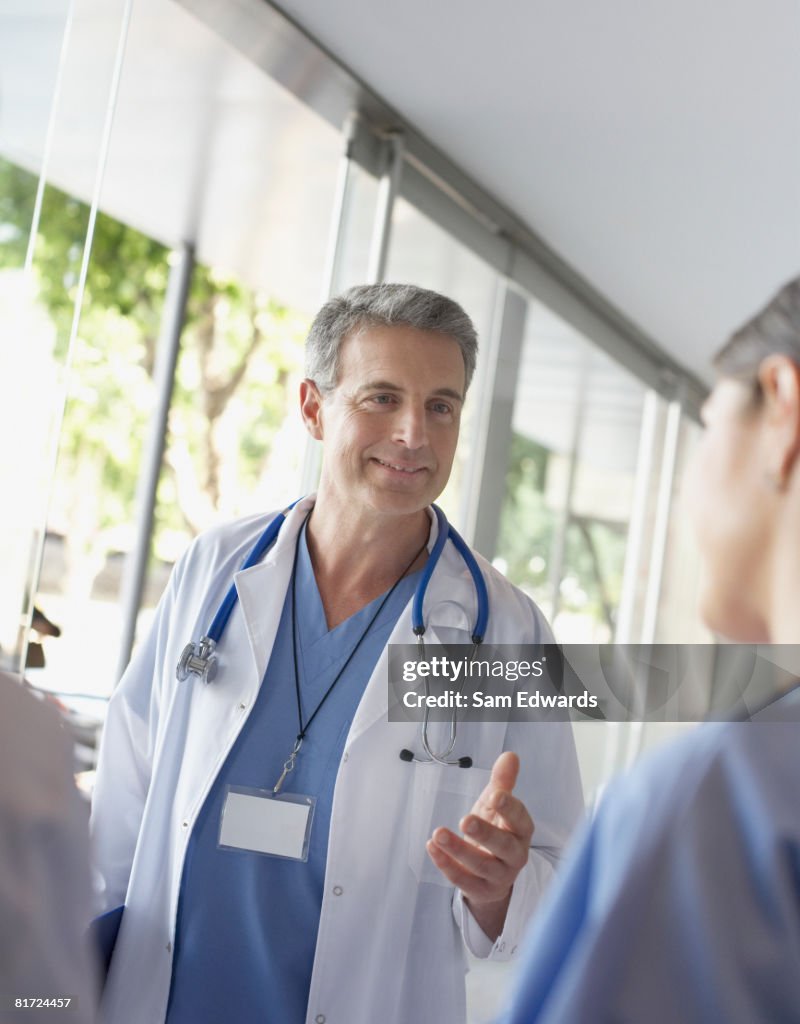 Doctor talking to hospital worker in corridor smiling