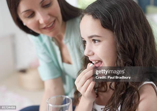 woman helping young girl take medicine in bedroom - 食藥 個照片及圖片檔