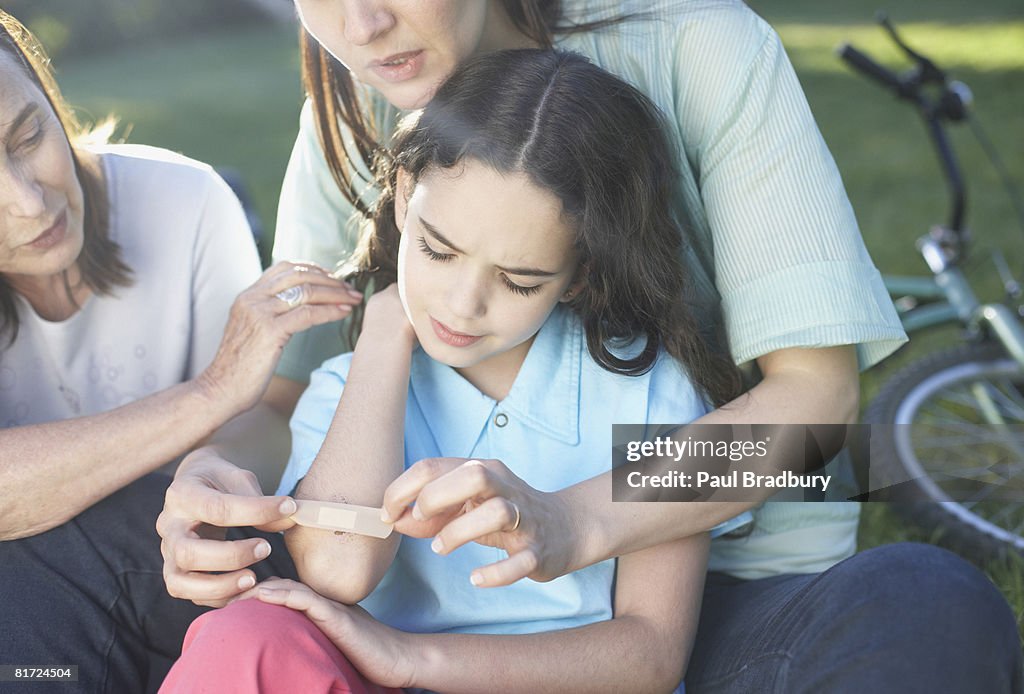 Two women helping an injured young girl who fell off her bike