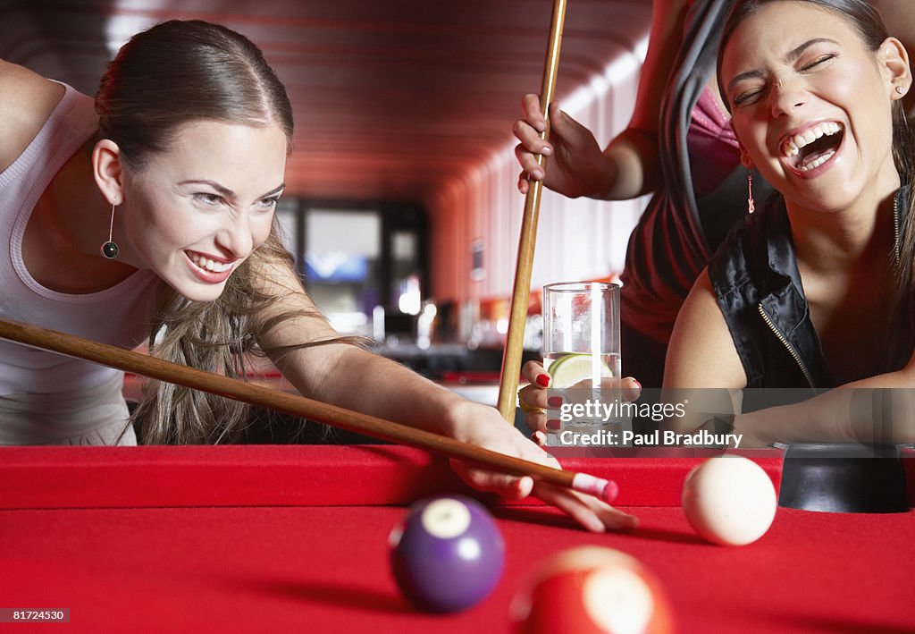 Three women playing pool and laughing