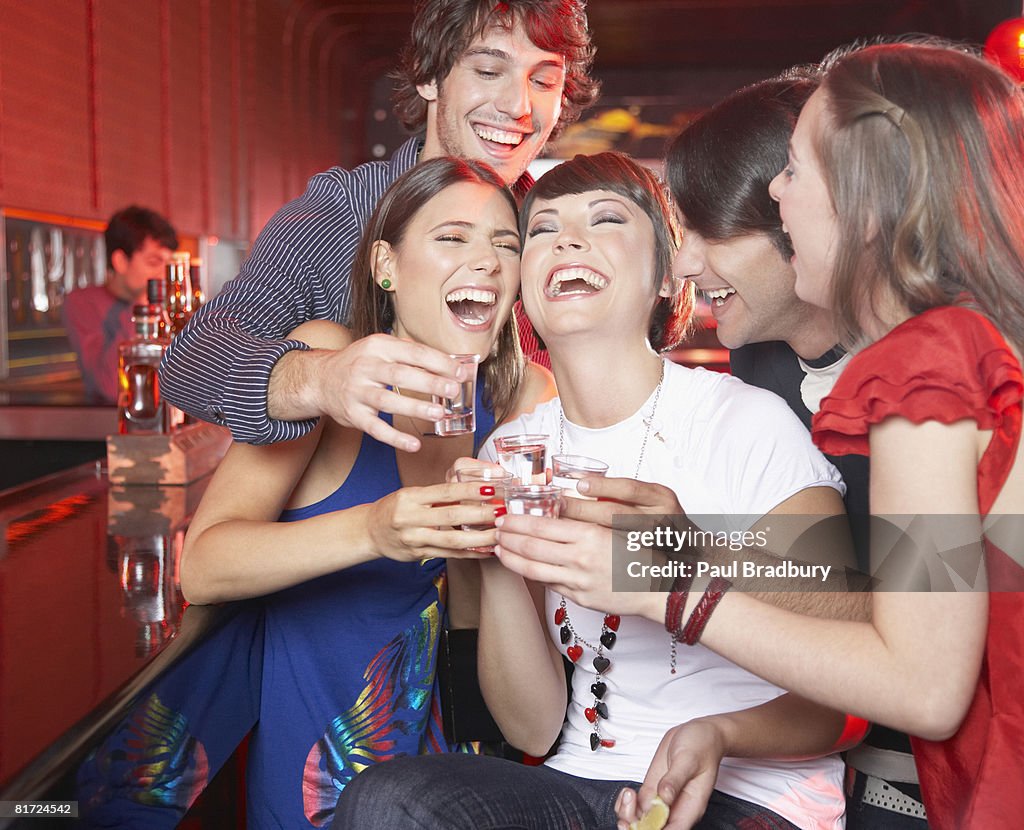 Five people with shots in nightclub toasting and smiling