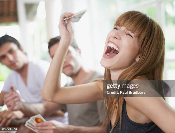 woman winning a card game to two friends at a table - championship day three stockfoto's en -beelden