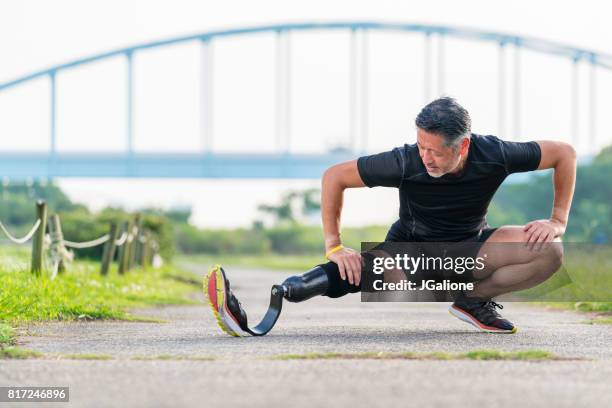 senior amputierte dehnen vor einem lauf - künstliches gliedmaß stock-fotos und bilder