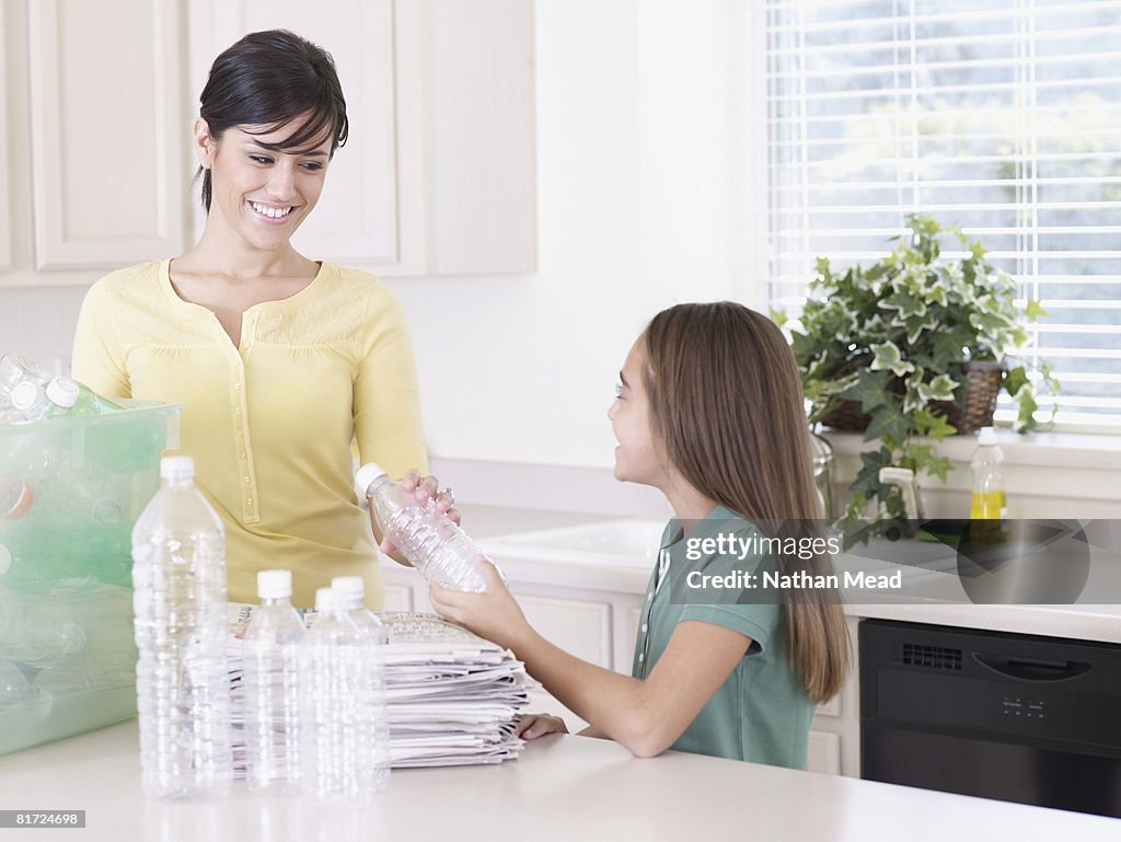 Woman and young girl in kitchen with recyclable materials smiling