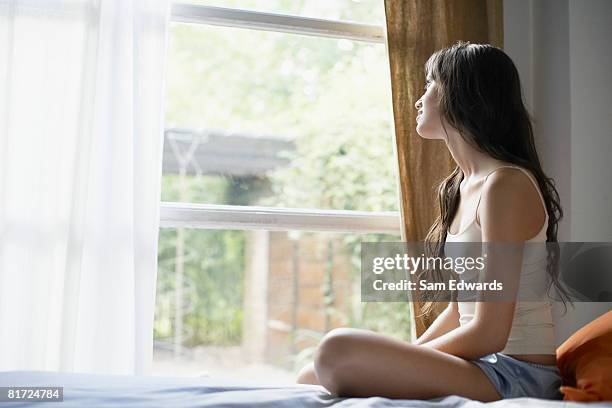 ベッドに座る女性窓の外 - tank top ストックフォトと画像