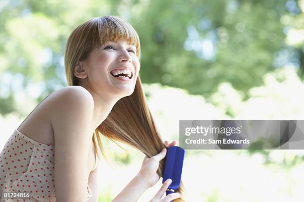 woman outdoors brushing hair and laughing - brushing hair stock pictures, royalty-free photos & images