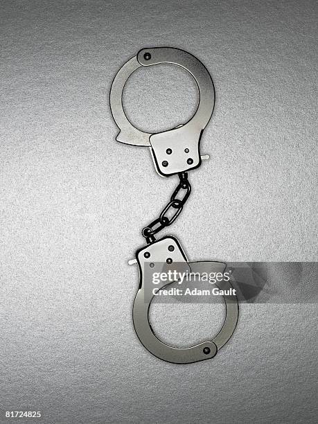 a pair of silver handcuffs - handcuffs stock-fotos und bilder