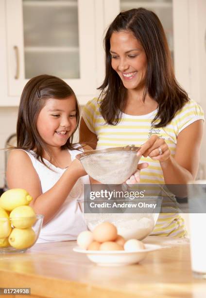 woman and young girl in kitchen sifting flour into a bowl and smiling - sifting stock pictures, royalty-free photos & images