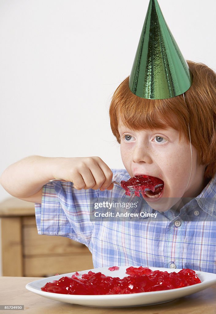 Young boy in kitchen eating jello