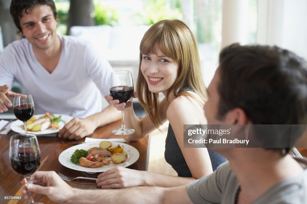 Trois personnes à dîner table de parler et sourire