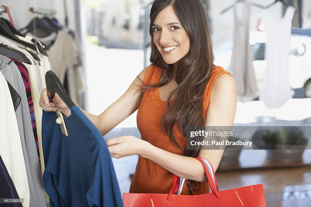 Mujer en tienda sonriente mirando a una camisa