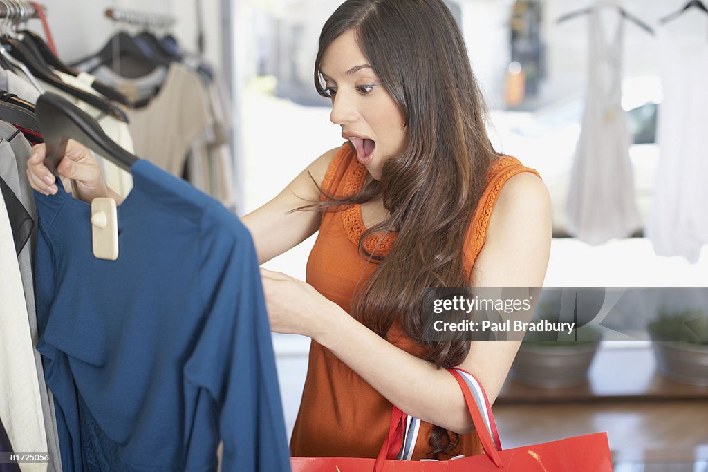 Woman in store looking at a shirt in shock