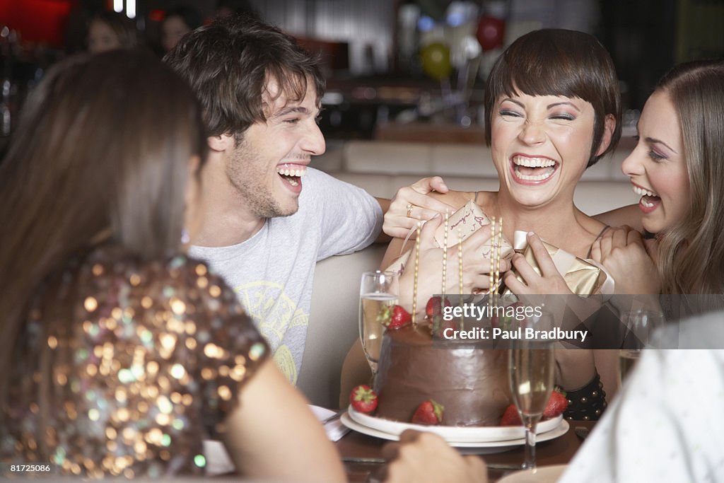 Five people having fun and laughing at a birthday party in a restaurant