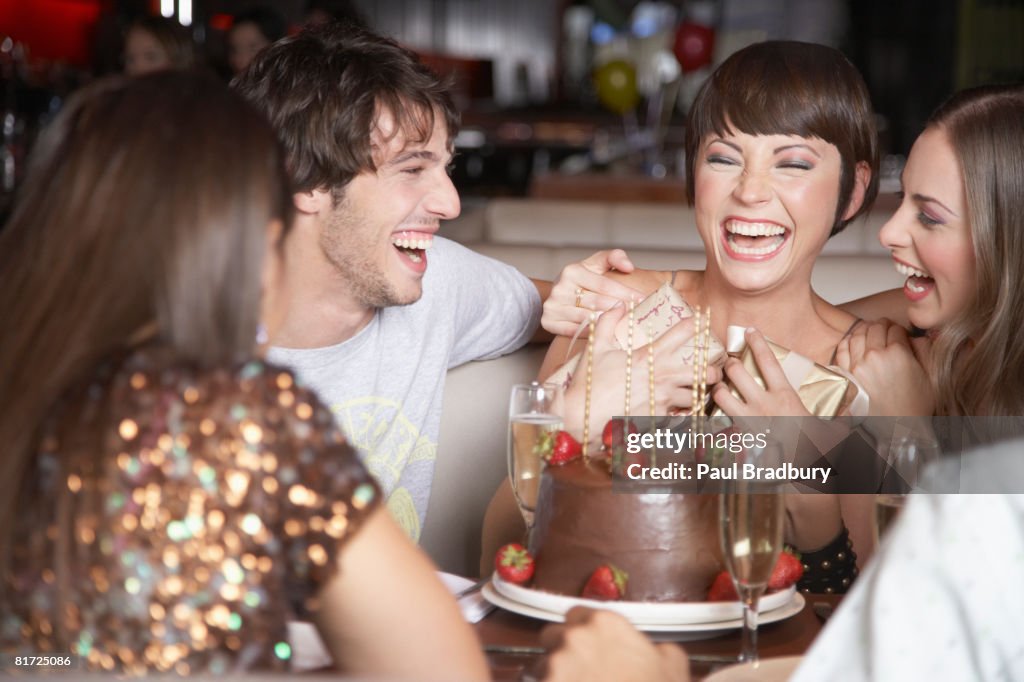 Five people having fun and laughing at a birthday party in a restaurant
