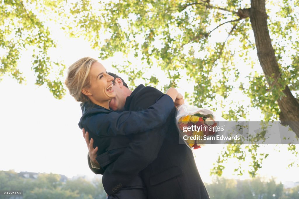 Couple embracing outdoors with flowers smiling