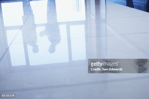reflection in floor of two doctors standing in hospital corridor - doctor in silhouette stock pictures, royalty-free photos & images