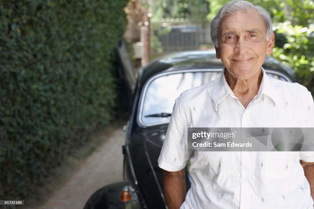 Senior man standing outdoors by car smiling