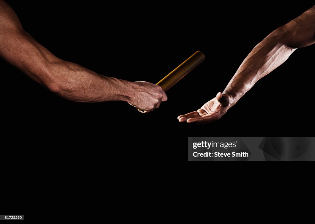 Two relay runners handing off a baton