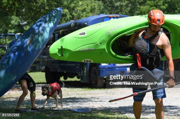 Marine Corps veteran and Army reservist John Dietle carries his kayak to Seneca Creek as he heads out to navigate the Potomac River on Sunday, July...