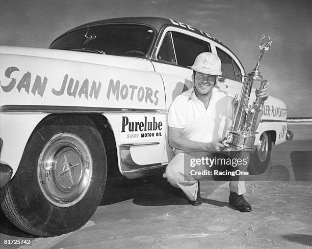 Lee Petty poses with his car and trophy after winning the race at the Palm Beach Speedway in his Dodge, just as he did a year earlier when he won...