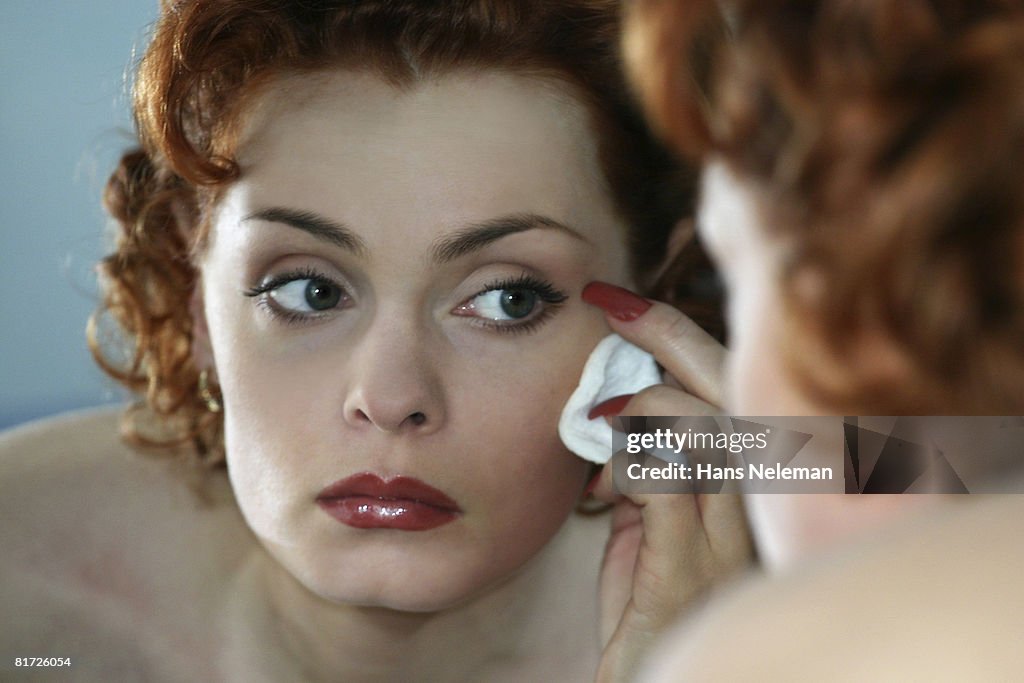 Woman looking in mirror wipes powder from face