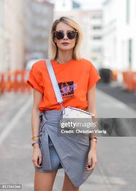 Lisa Hahnbueck wearing an orange tshirt from Urban Outfitters with the print follow the Zeitgeist, a grey plaid asymmetric skirt Storets a white...