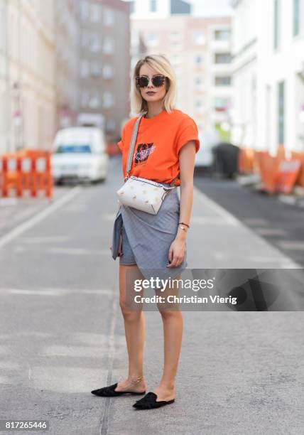 Lisa Hahnbueck wearing an orange tshirt from Urban Outfitters with the print follow the Zeitgeist, a grey plaid asymmetric skirt Storets a white...