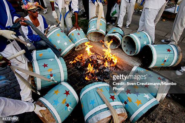 Cuban musicians warm up their drums at an open fire during the Camaguey carnival June 25, 2008 in Camaguey, Cuba. The first day celebration of the...