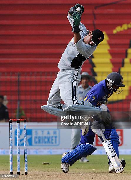 United Arab Emirates' cricketer Anjad Ali jumps in the air to receive a throw as Sri Lanka cricketer Chamara Silva reaches his crease during a Group...