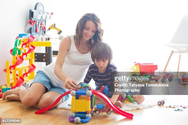 cute pregnant mother and child boy playing together indoors at home with toys - family inside car fotografías e imágenes de stock