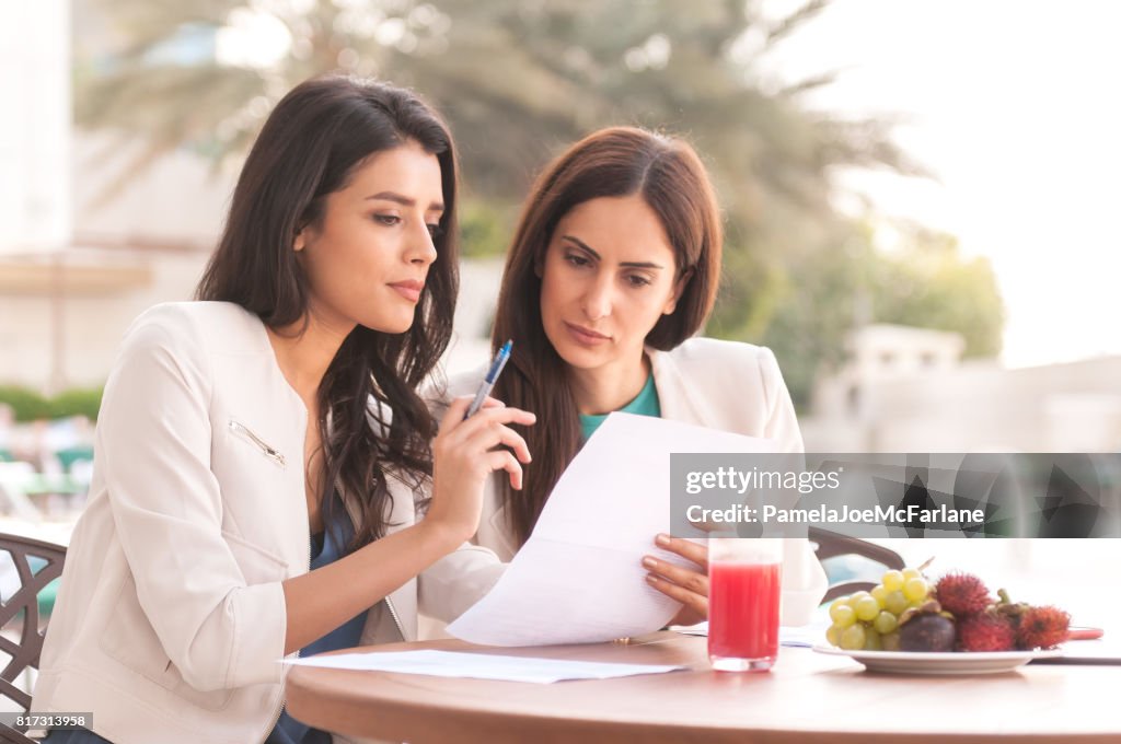 Millenial Arab Businesswomen Reviewing Contract During Business Lunch at Hotel