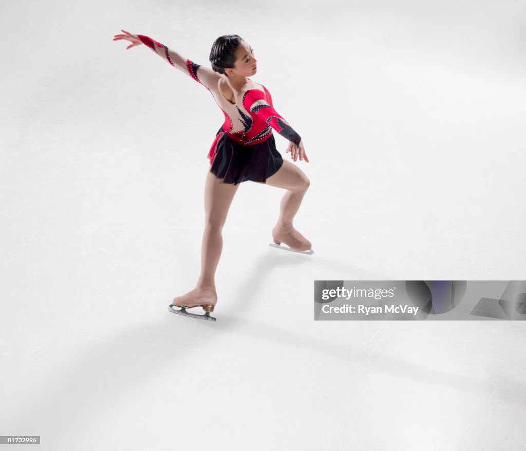 Young woman figure skater skating - performing a Bauer.