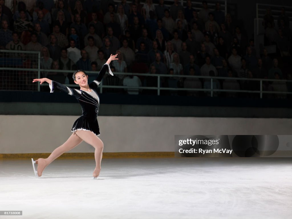 Young woman figure skater standing in finishing pose.