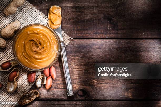 peanut butter in a glass bowl shot on rustic wooden table - peanut butter stock pictures, royalty-free photos & images