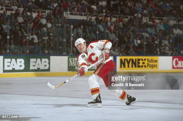 Canadian ice hockey player Al MacInnis of the Calgary Flames fires the puck along the ice during a game, early 1980s to early 1990s.