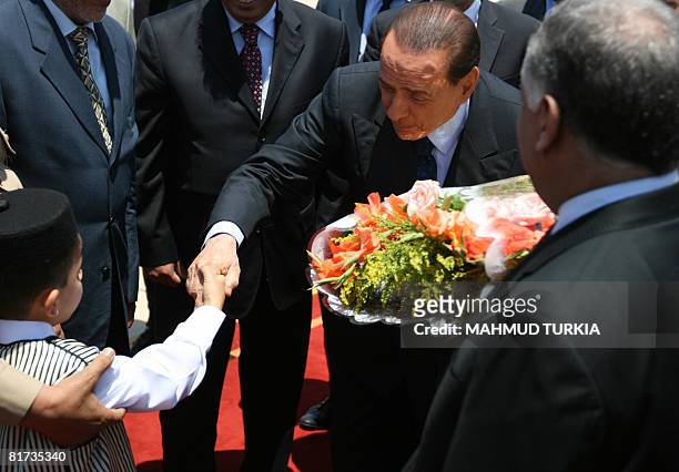 Italy's Prime Minister Silvio Berlusconi shakes hands with a Libyan child upon his arrival in the port city of Sirte, 600 kms east of Tripoli, for...