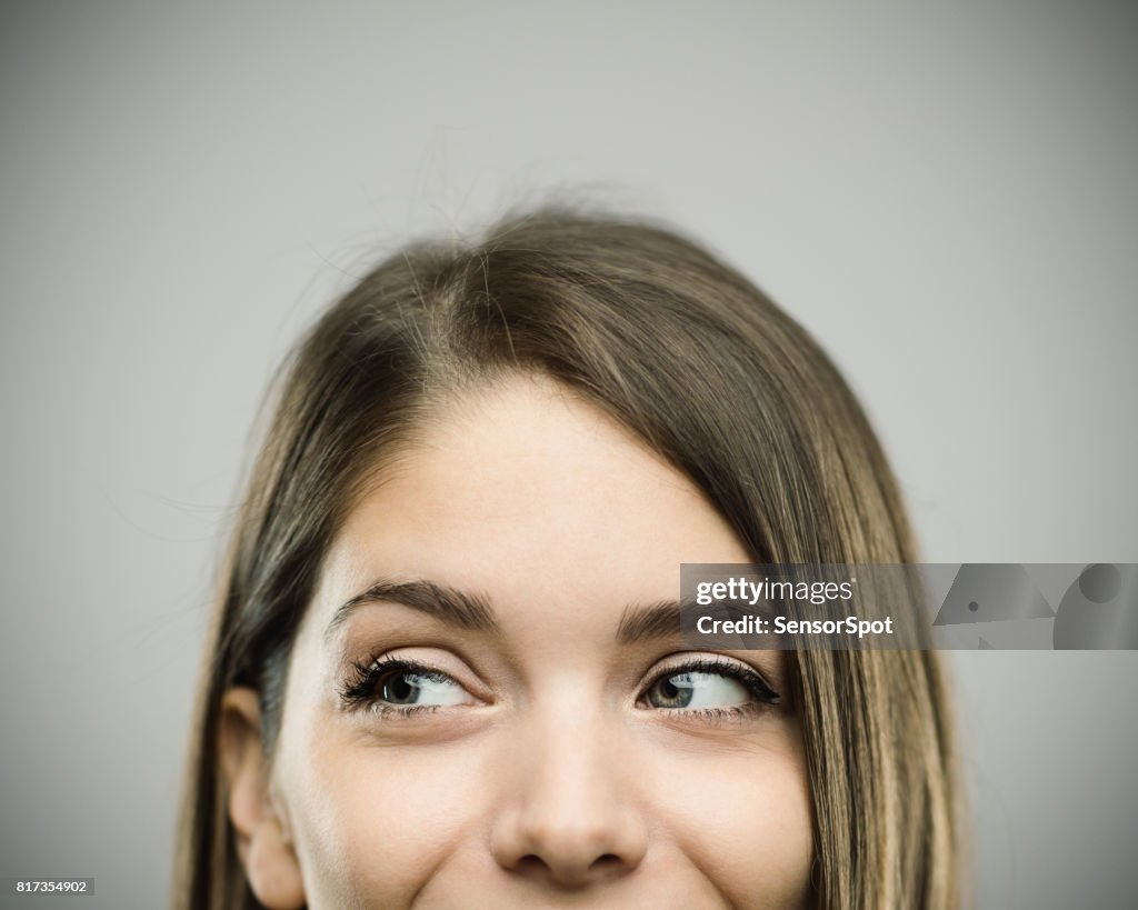 Real happy young woman studio portrait looking away