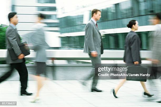 male and female professionals walking on sidewalk, blurred motion - moving past ストックフォトと画像