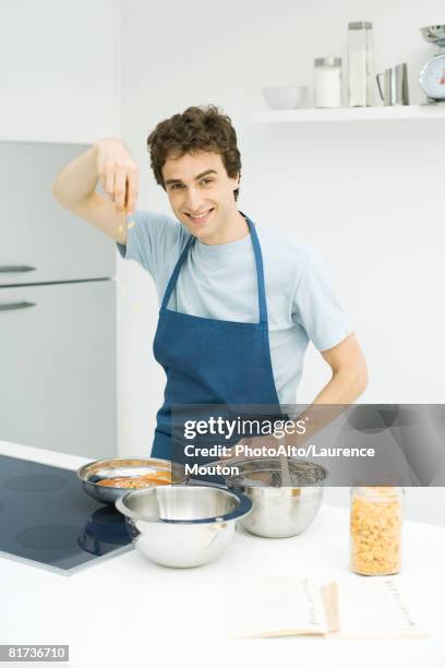 young man cooking, smiling at camera - mixing bowl stock pictures, royalty-free photos & images