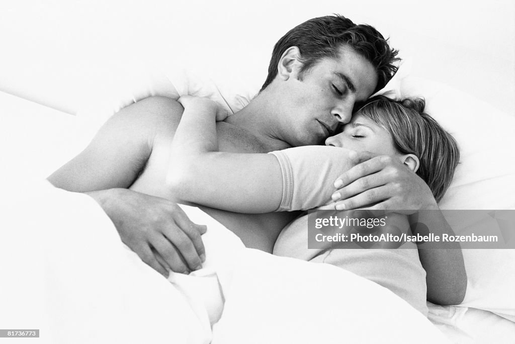 Couple embracing in bed, eyes closed